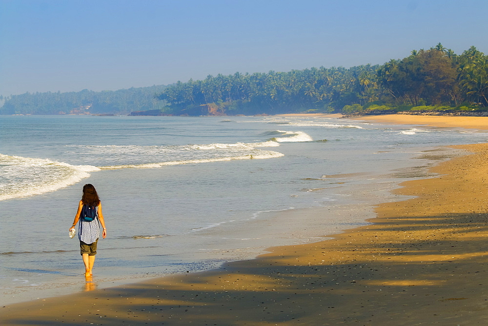 Lone traveller on lovely palm-fringed, Kizhunna Beach, south of Kannur on Kerala's north coast, Kizhunna, Kannur, Kerala, India, Asia