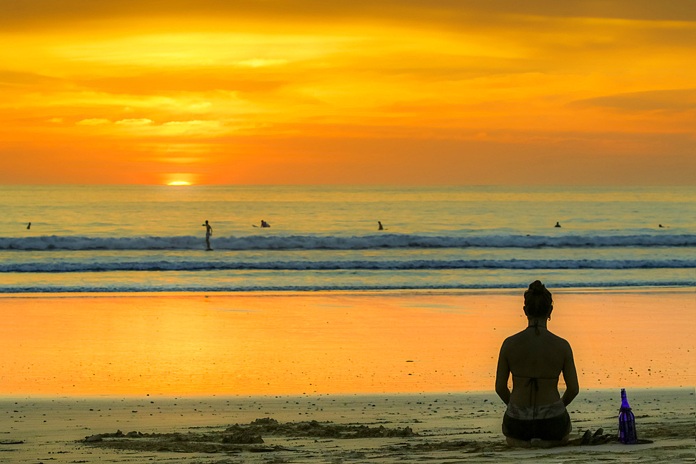 Girl and surfers silhouetted by sunset at this hip surf beach and yoga destination, Playa Guiones, Nosara, Guanacaste, Costa Rica, Central America