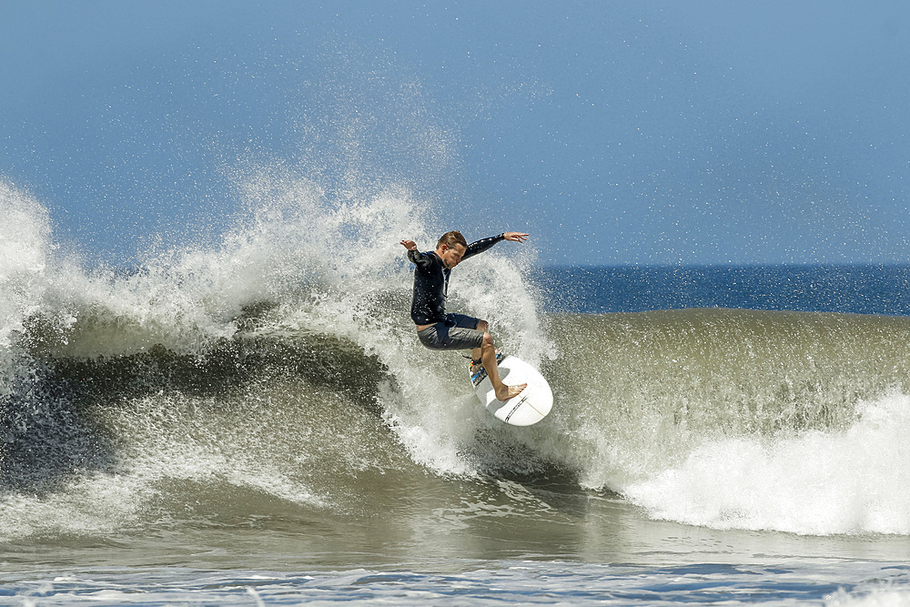 Shortboard surfer rides a wave at this fast-growing surf beach and yoga destination, Playa Guiones, Nosara, Guanacaste, Costa Rica, Central America