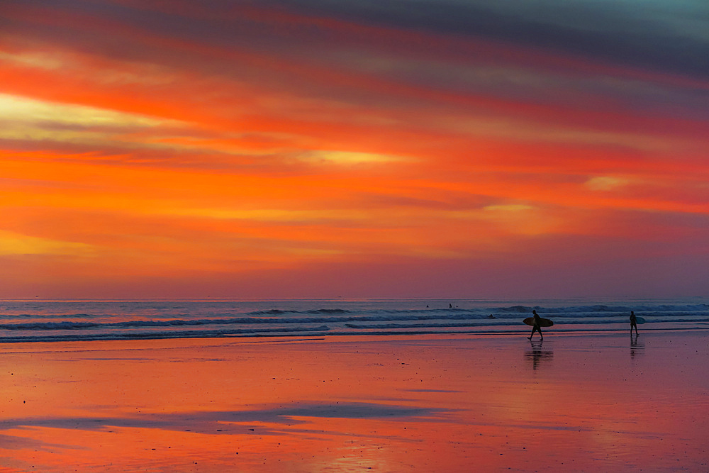 Surfer silhouetted on Guiones Beach where many come to relax and surf at sunset, Playa Guiones, Nosara, Guanacaste, Costa Rica, Central America