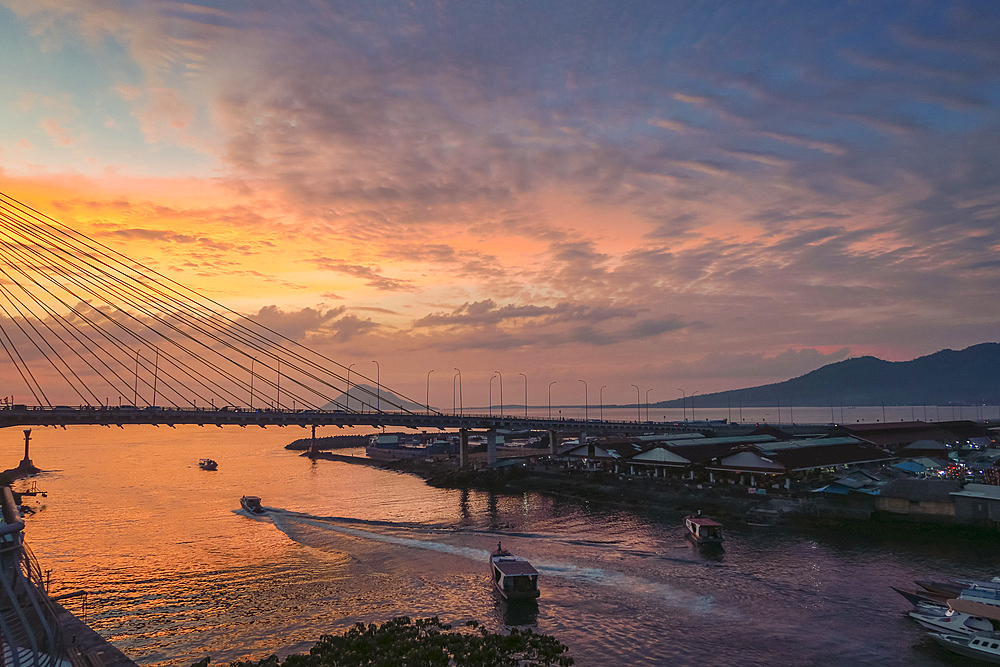 Manado port and Soekarno Bridge with Manadotua Island beyond at sunset in provincial capital of Sulawesi's far north, Manado, North Sulawesi, Indonesia, Southeast Asia, Asia