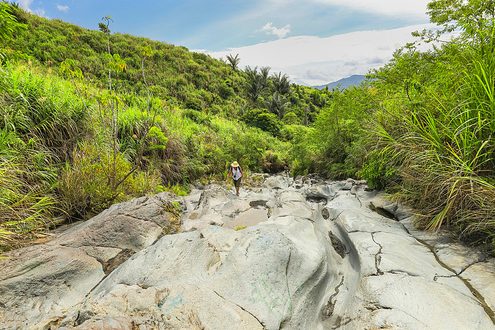 Walker on an old lava flow, now a smooth eroded river bed and hiking trail to Lokon volcano, near Tomohon city, Gunung Lokon, Tomohon, North Sulawesi, Indonesia, Southeast Asia, Asia