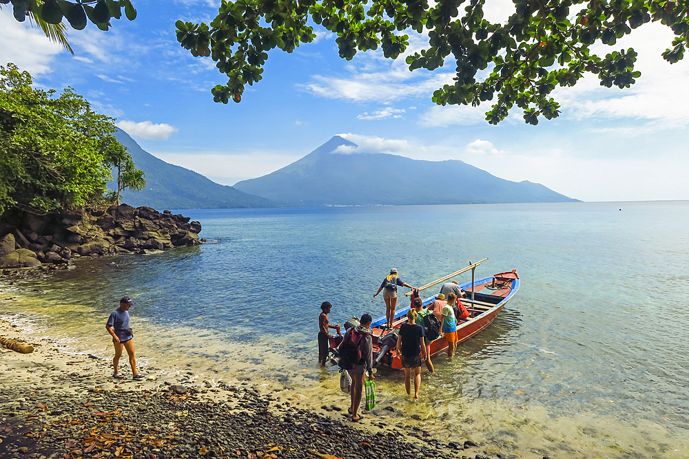 Tourists departing on a boat trip from Kalea Beach with active Karangetang volcano beyond, Kalea, Siau Island, Sangihe Archipelago, North Sulawesi, Indonesia, Southeast Asia, Asia