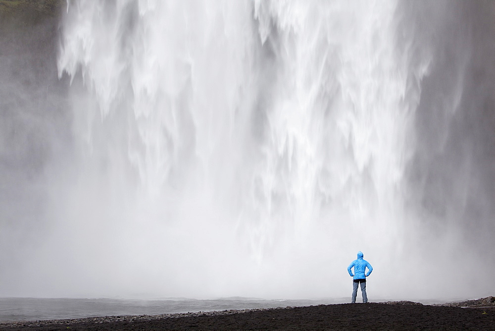 Skogafoss waterfall with a hiker, Skogar, South Iceland, Iceland, Europe