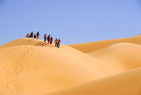 Group of tourists descent a sanddune Mandara Libya