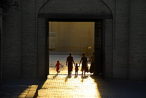 Human silhouettes against sunlight in the Ota Darvoza Gate in the old town Khiva Uzbekistan