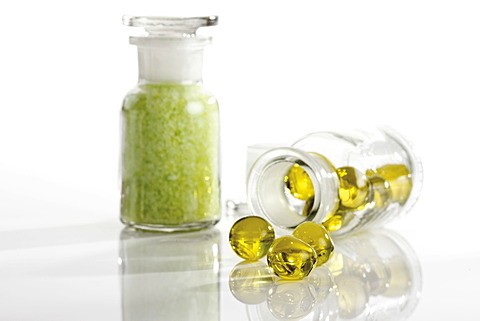 Glass bottles containing golden bath oil beads and green bath salt crystals