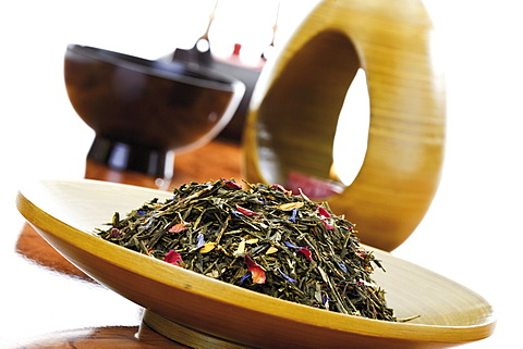 Green tea mixture in a wooden bowl and an Asian tea set