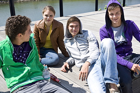 Three boys and a girl sitting on the floor, relaxing in the sun