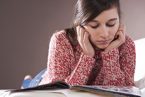 Girl lying on a couch and reading a magazine