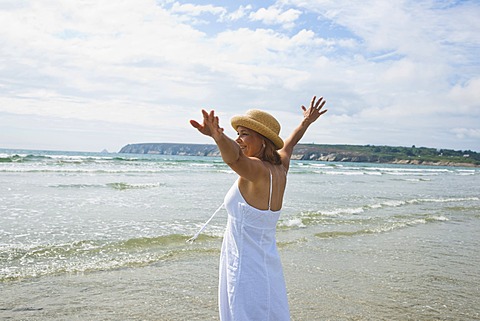 Woman standing with her arms outstretched on a beach