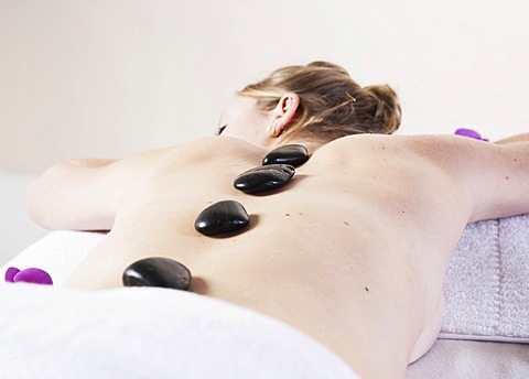 Young woman being treated with hot stones, hot stone massage