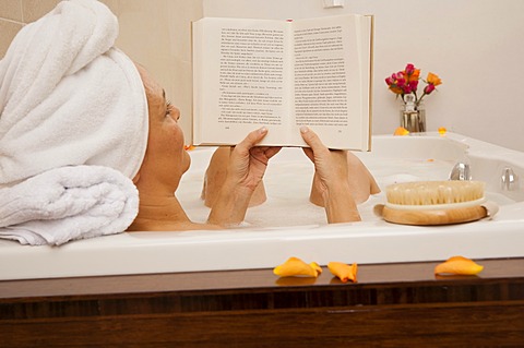 Woman taking a bath and reading a book