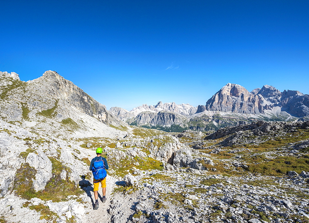 Hiker with climbing helmet on footpath to the Nuvolau, view of the Nuvolau summit and mountain range Tofane, Dolomites, South Tyrol, Trentino-Alto Adige, Italy, Europe