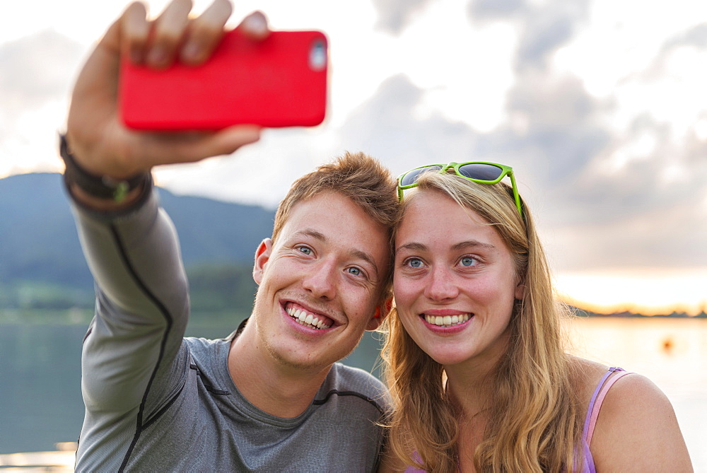 Young couple photographing themselves with mobile phone, selfie, Schliersee, Upper Bavaria, Bavaria, Germany, Europe