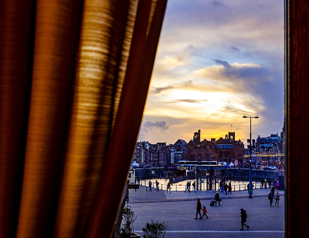 View of the station forecourt through a window with curtain, evening, Amsterdam, The Netherlands, Europe