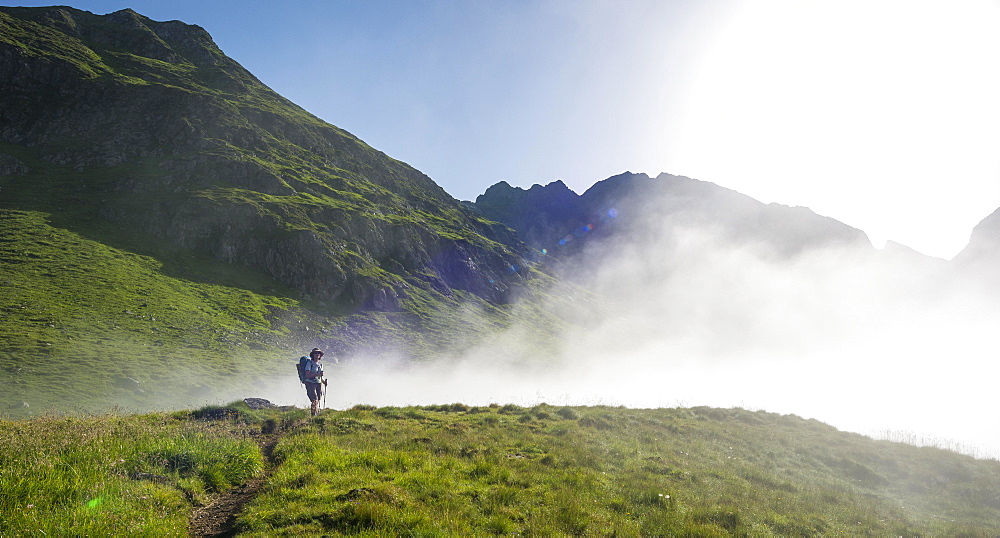 Hiker on the Schladminger Höhenweg with rising clouds of fog, Schladminger Tauern, Schladming, Steiermark, Austria, Europe