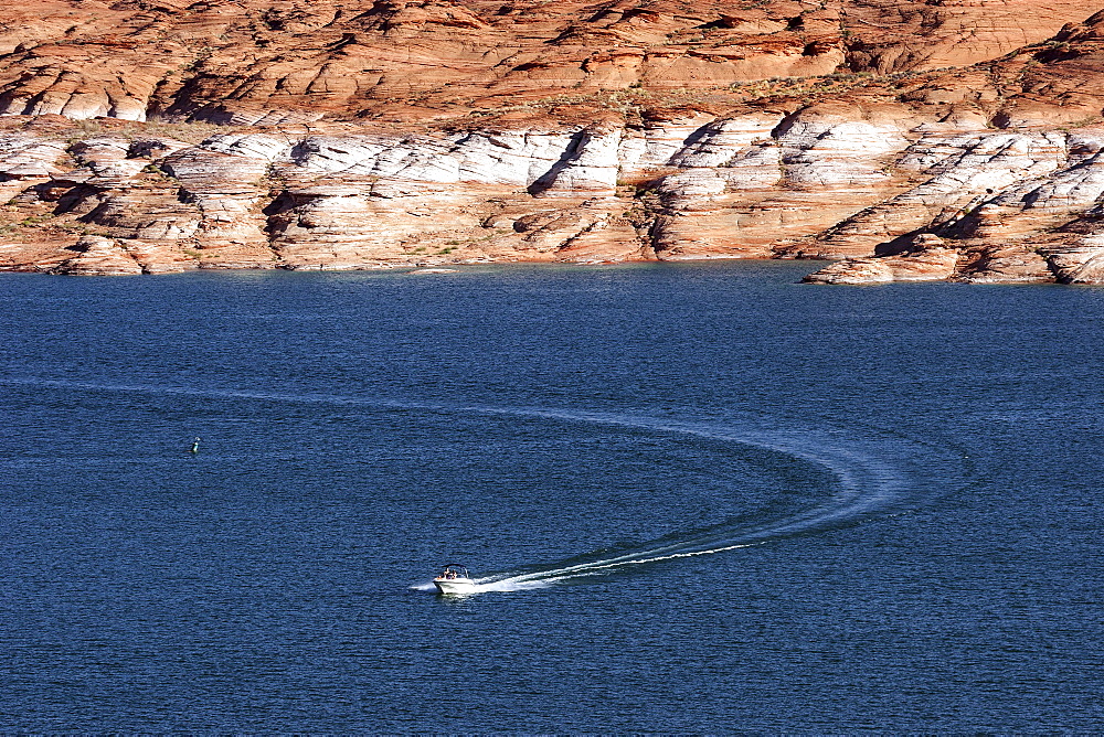 Boat on Lake Powell, red Navajo Sandstone cliffs behind, Page, Arizona, USA, North America