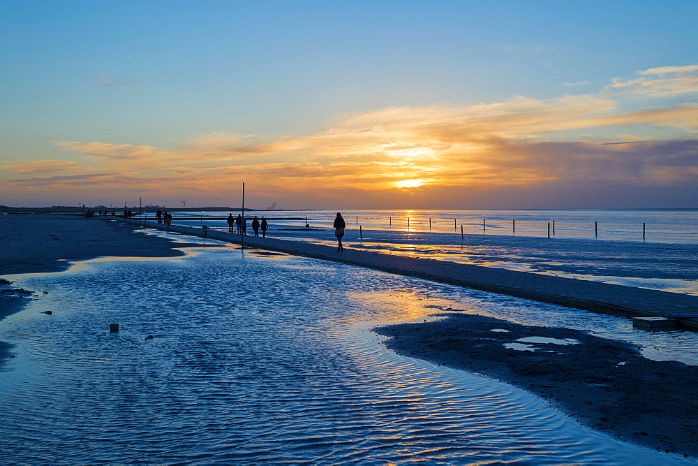 Beach walkers at the Wadden Sea on the North Sea coast in the blue hour at sunset, Norddeich, Lower Saxony, Germany, Europe