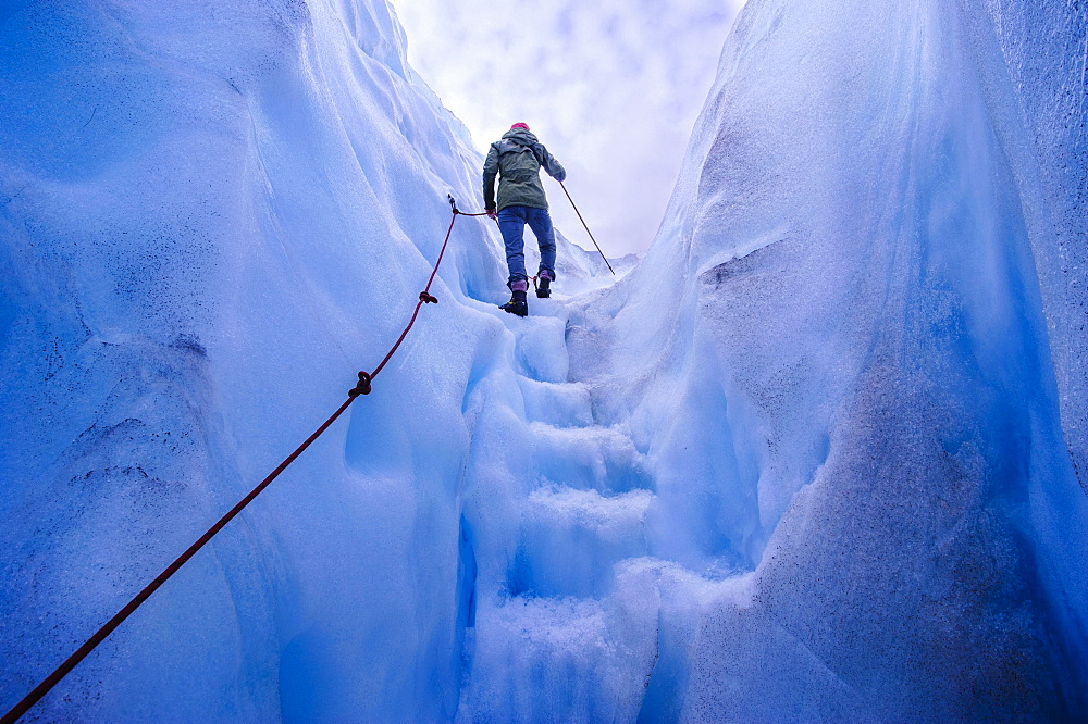 Woman walking steps out of a ice cave in Fox Glacier, South Island, New Zealand, Oceania