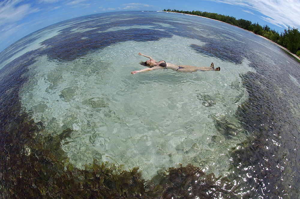 A young woman lying in the water on her back, Denis Island, Seychelles, Africa