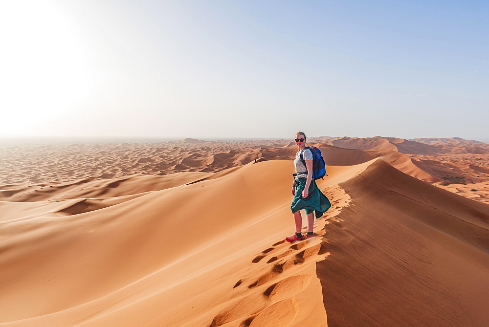 Female hiker on a red sand dune in the desert, dune landscape Erg Chebbi, Merzouga, Sahara, Morocco, Africa