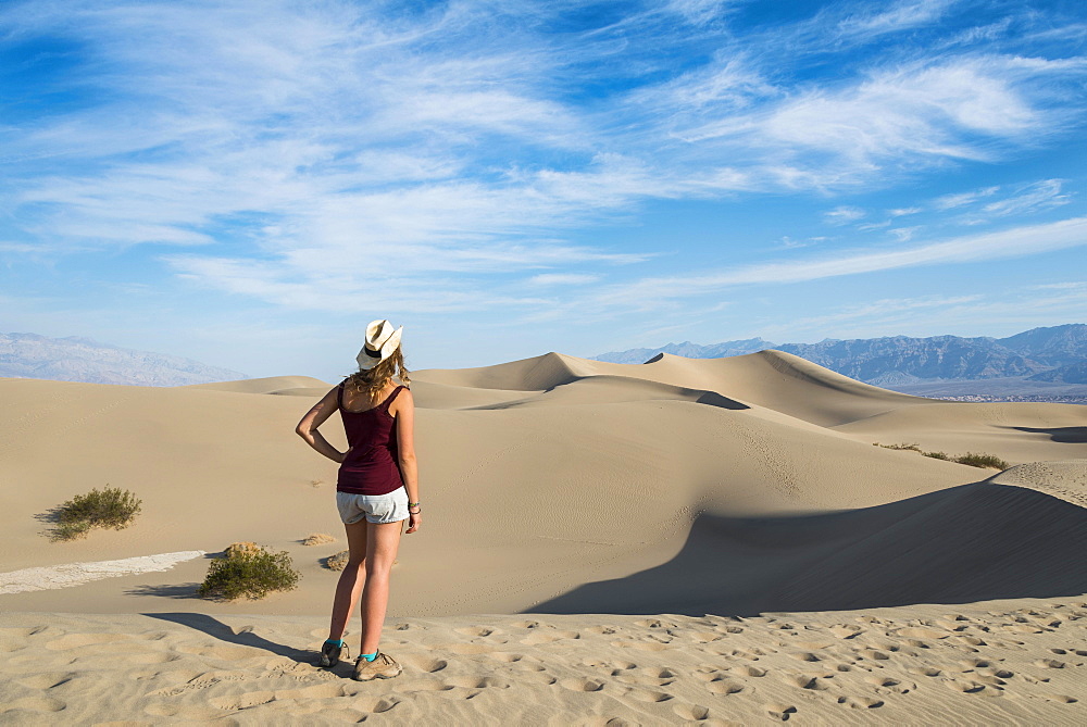 Female tourist overlooking the Mesquite Flat Sand Dunes, sand dunes, foothills of Amargosa Range Mountain Range behind, Death Valley, Death Valley National Park, California, USA, North America