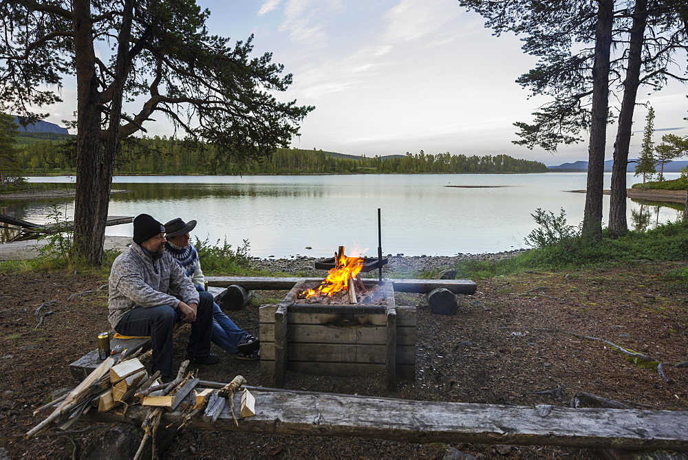 Couple sitting at a campfire, campsite on Arrenjarka island, Kvikkjokk, Norrbotten County, Sweden, Europe