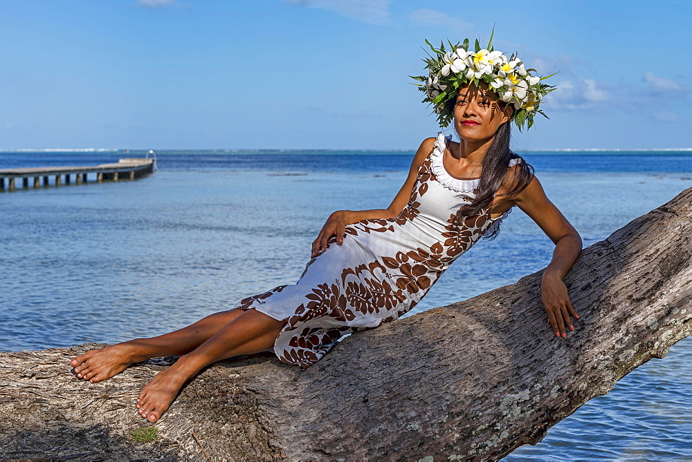 Young woman with flower wreath from Frangipani leaning on palm trunk, Raiatea, French Polynesia, Oceania