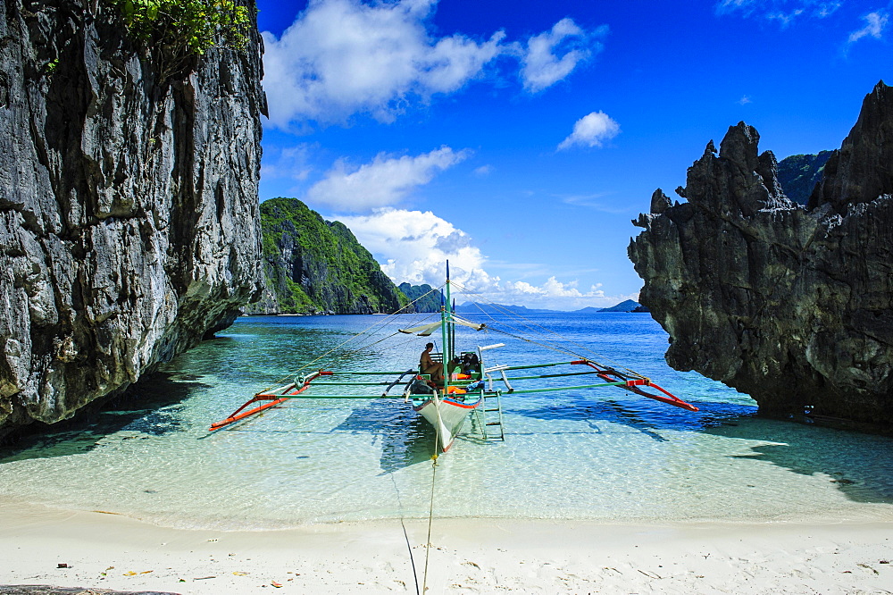 Outrigger boat on a little white beach and crystal clear water in the Bacuit archipelago, Palawan, Philippines, Asia