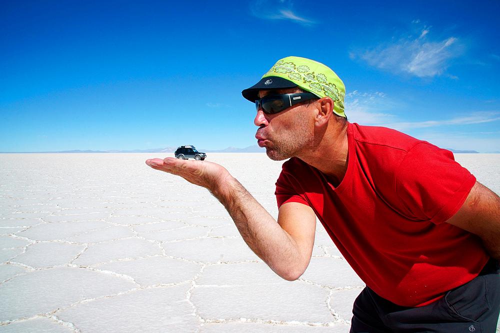 Optical illusion, man holds off-roader on hand, Salar de Uyuni, Uyuni, Potosi, Bolivia, South America