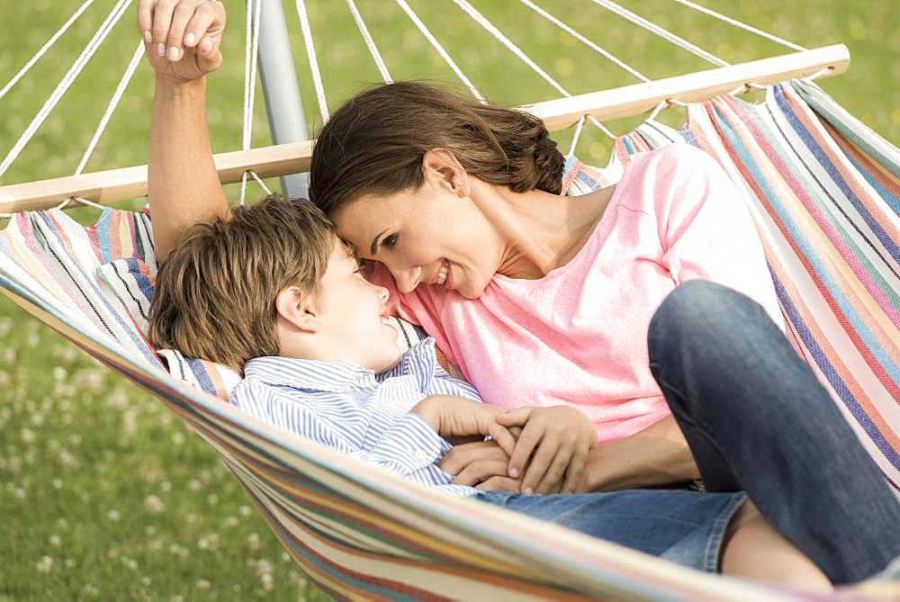 Mother and son lying in hammock, cuddling, Germany, Europe