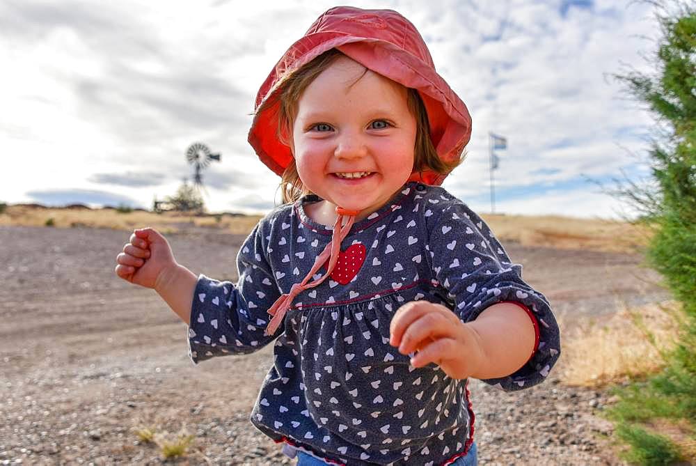 Little girl with red hat running and laughing, Patagonia, Argentina, South America