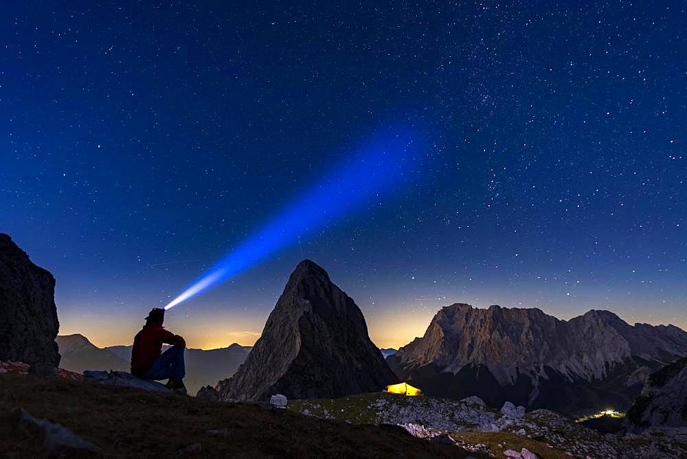 Summit of the Sonnenspitze with mountaineer and tent as well as Zugspitze in the background with blue hour and starry sky, Ehrwald, Ausserfern, Tyrol, Austria, Europe