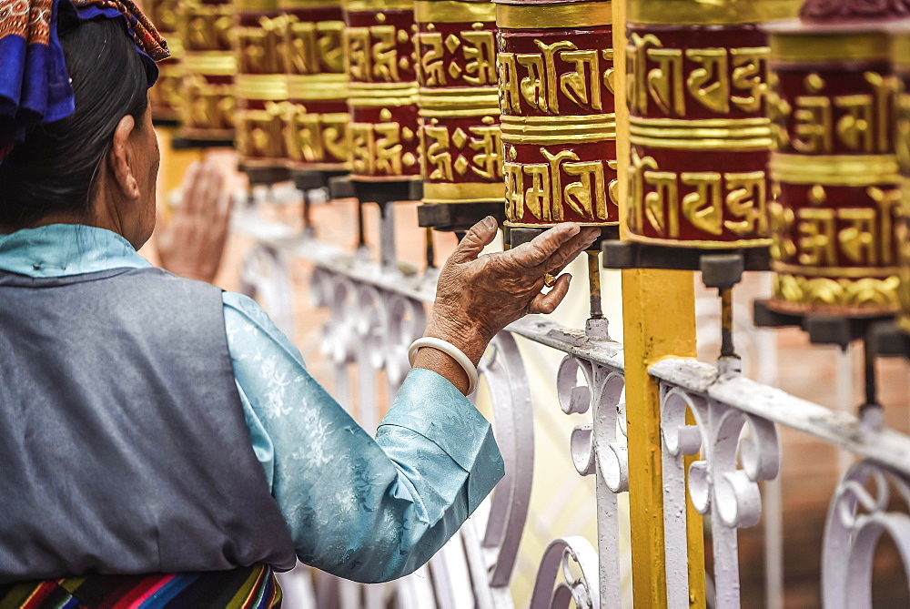 Woman turns on prayer wheels, temple, Pokhara, Nepal, Asia