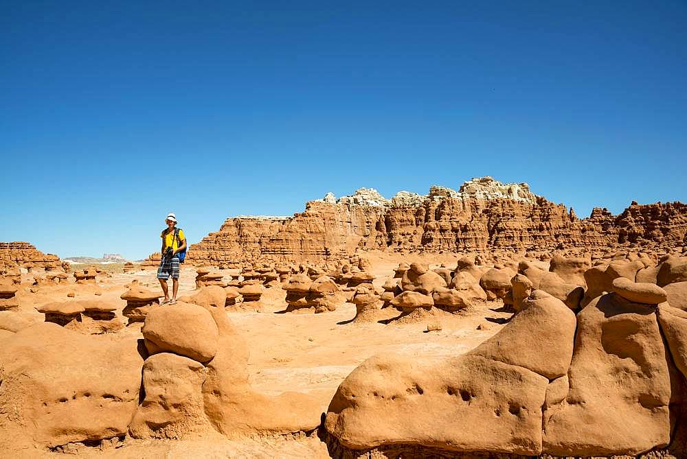 Tourist, young man likes Hodoo, eroded Hoodoos, rock formation of Entrada sandstone, Goblin Valley State Park, San Rafael Reef, Utah, southwest, USA, North America