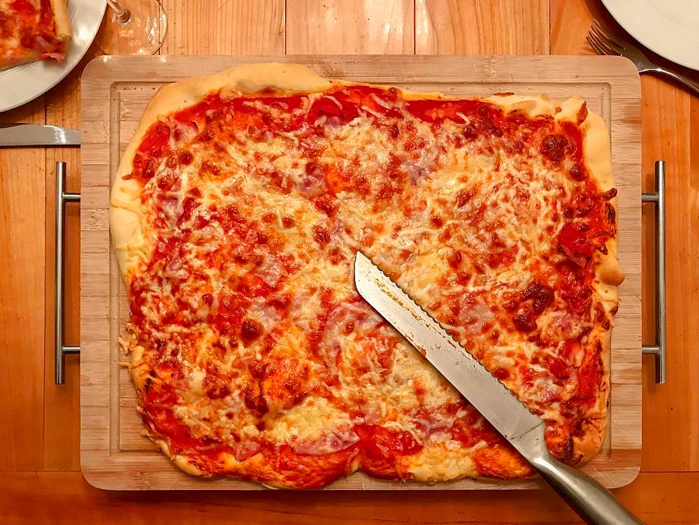 Homemade pizza with tomatoes and cheese on wooden board, Germany, Europe