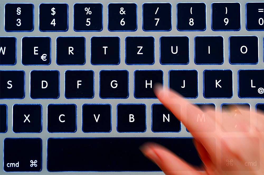 Hand taps computer keyboard, motion blur, Germany, Europe