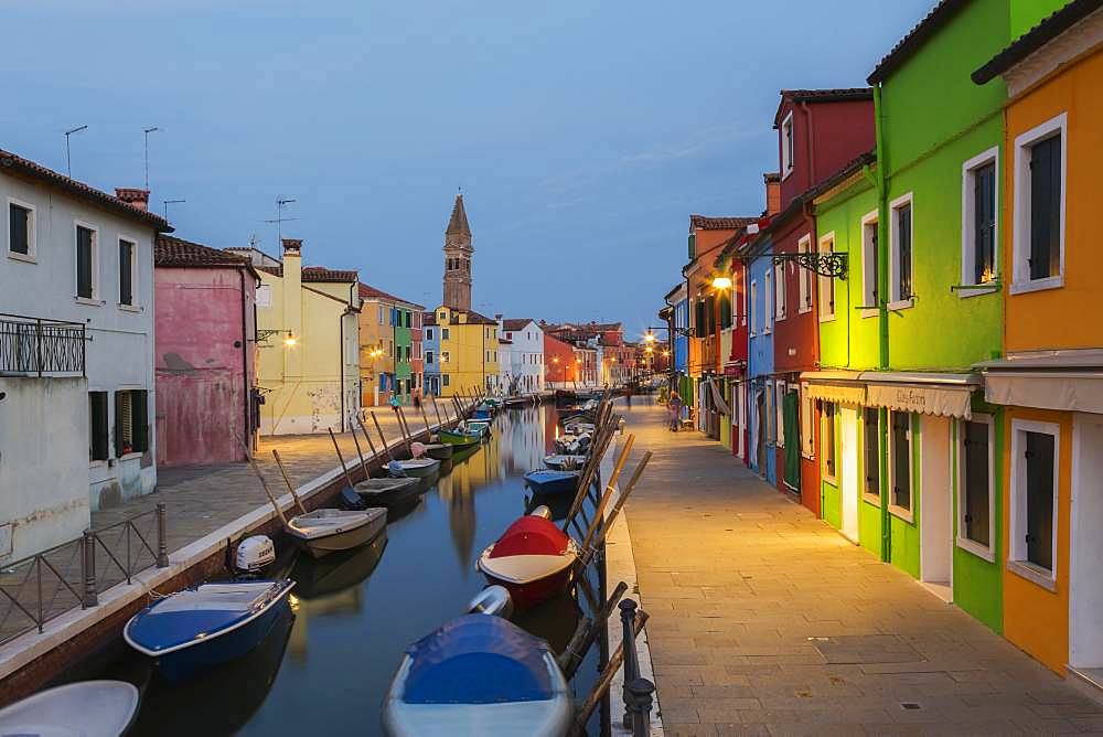 Moored boats on canal lined with colourful houses, behind San Martino church at dusk, Burano Island, Venetian Lagoon, Venice, Veneto, Italy, Europe