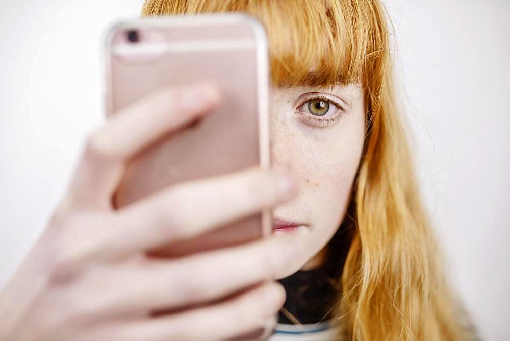 Girl, teenager, with smartphone, looks thoughtful, studio shot, Germany, Europe