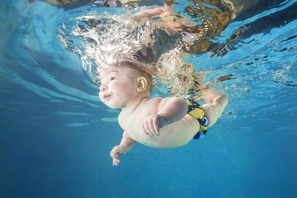 Baby boy diving in the pool, water sports for child development, Ukraine, Europe