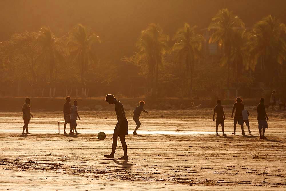 Young people playing football on the beach, evening light, Playa Samara, Samara, peninsula Nicoya, province Guanacaste, Costa Rica, Central America