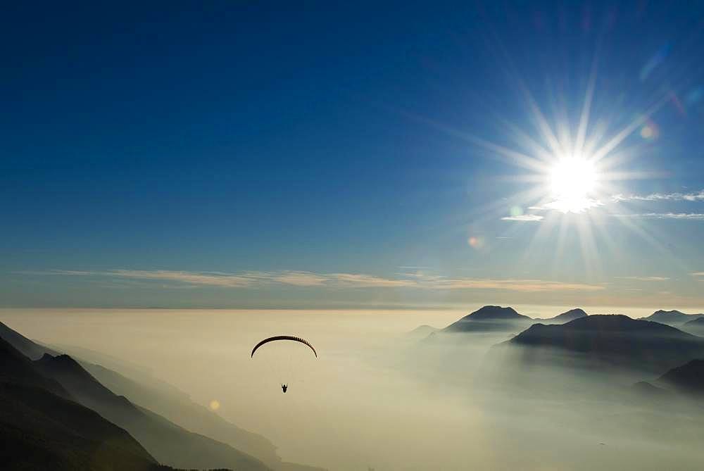 Paraglider over the mountains in clouds, near Malcesine at Lake Garda, aerial view, Veneto, Italy, Europe