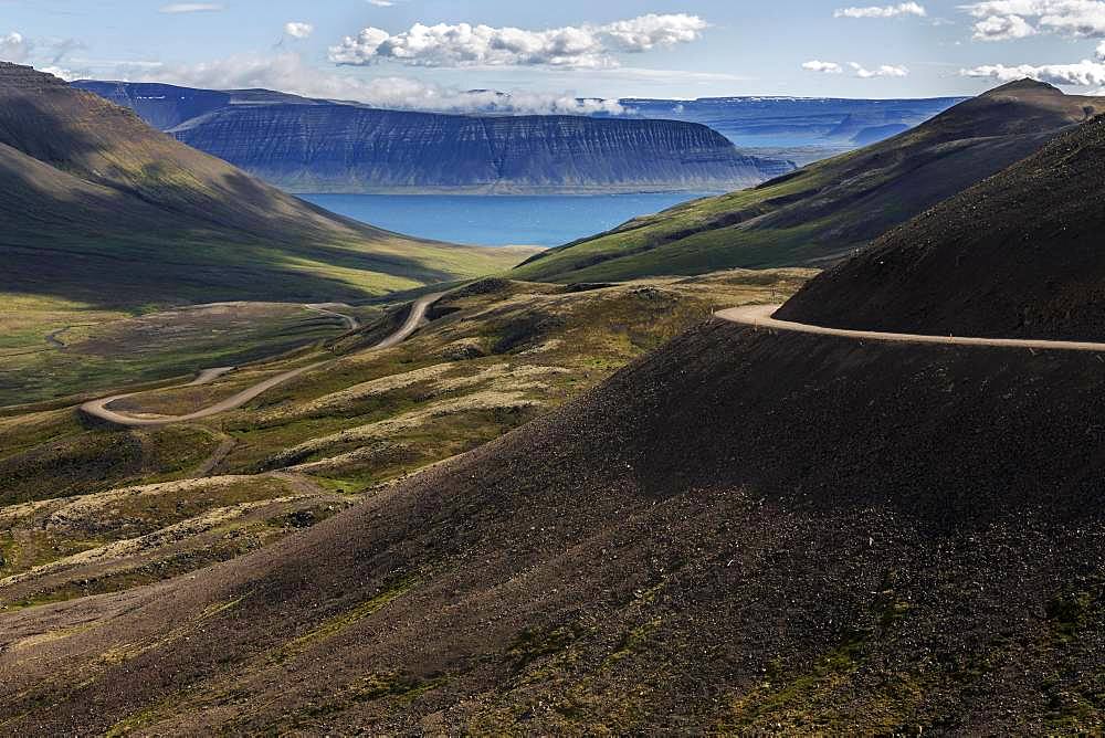 Gravel road meanders through volcanic landscape, near Hrafnseyri, Westfjords, Iceland, Europe