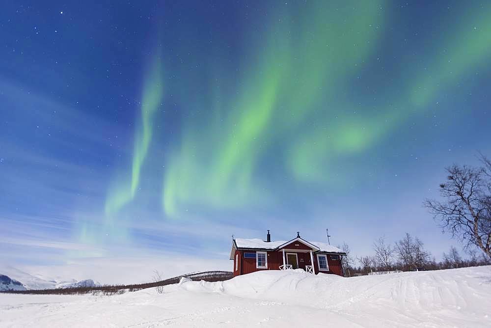 Northern Lights (Aurora borealis) above a Swedish red house in winter, Kungsleden, Province of Lapland, Sweden, Europe
