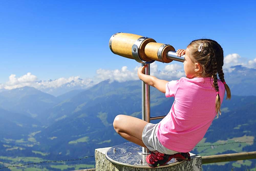 Girl looking through a wooden telescope, summit panorama path of the Hohe Salve, Hopfgarten, Brixental, Kitzbuehel Alps, Tyrol, Austria, Europe