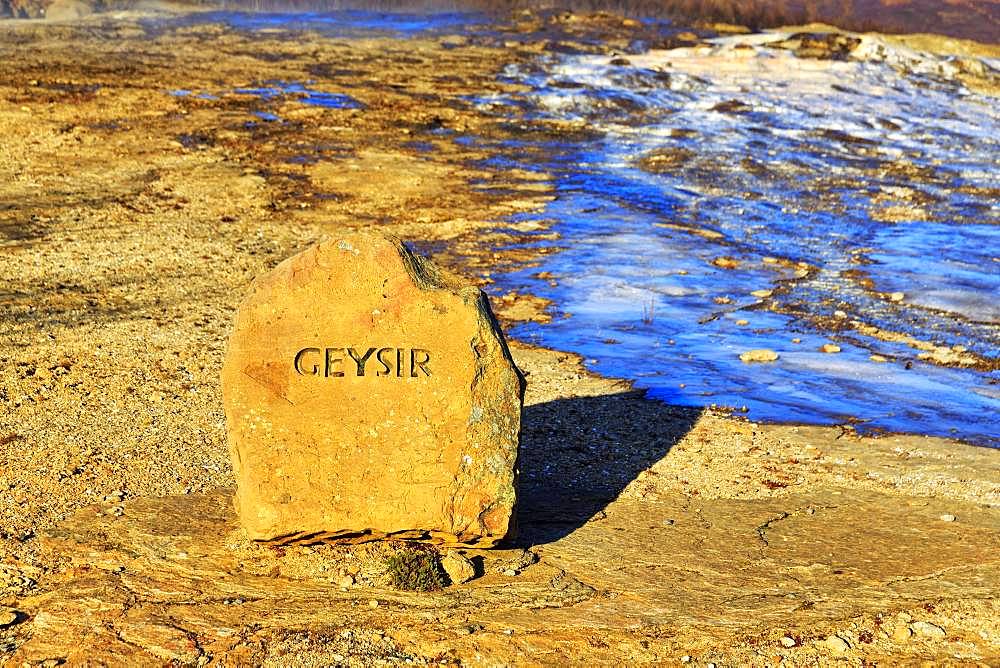 Red stone with the inscription Geysir, next to a frozen water surface, high temperature area Haukadalur, Golden Circle, South Iceland, Iceland, Europe