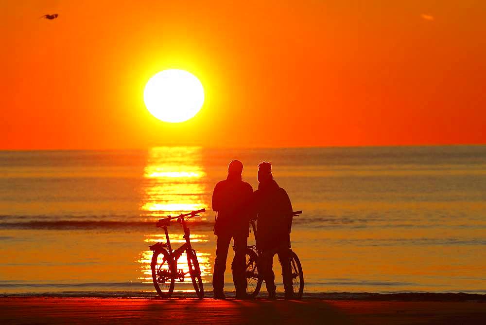 Couples with bikes on the beach watching the sunset, North Sea, St. Peter-Ording, North Sea coast, Schleswig-Holstein Wadden Sea National Park, Schleswig-Holstein, Germany, Europe