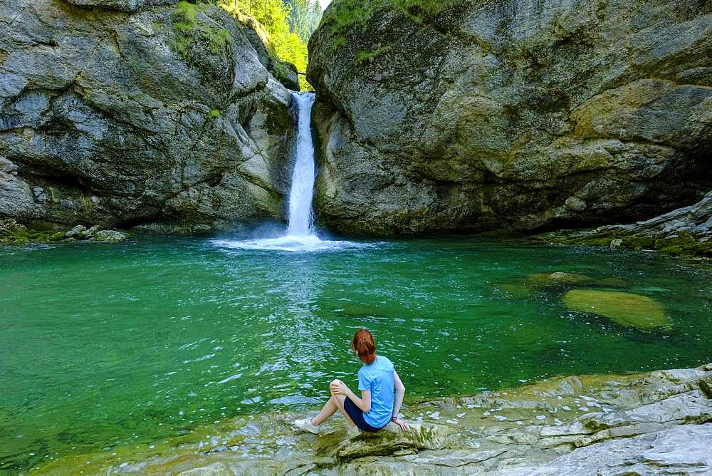 Young woman sitting in front of Buchenegger waterfalls near Oberstaufen, Oberallgaeu, Allgaeu, Swabia, Bavaria, Germany, Europe