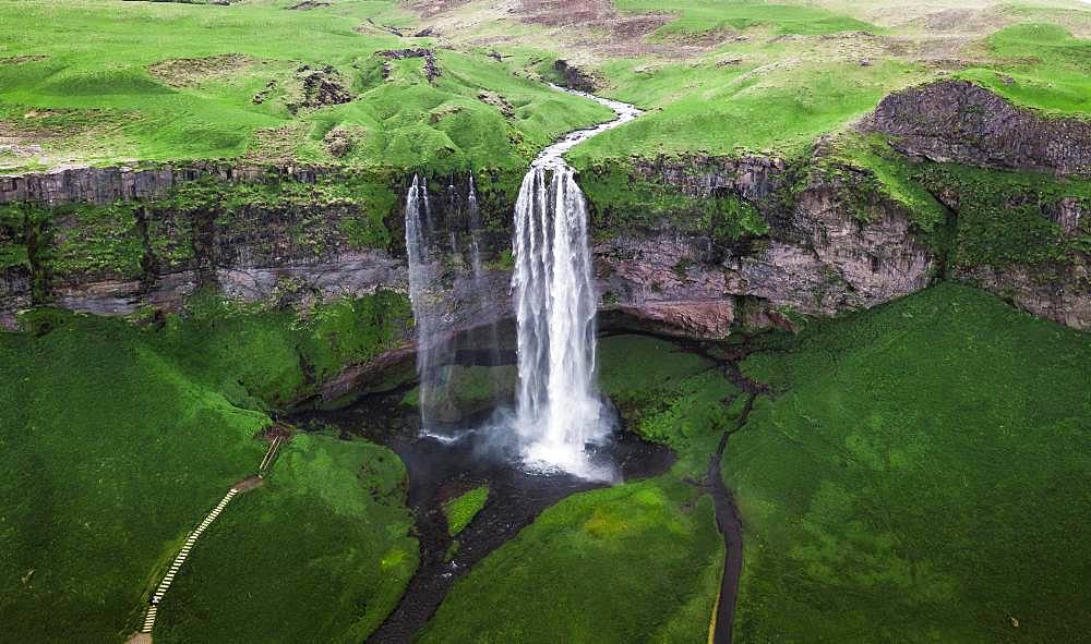 Aerial view, Seljalandsfoss waterfall falls from high cliff, green grass landscape, South Iceland, Iceland, Europe